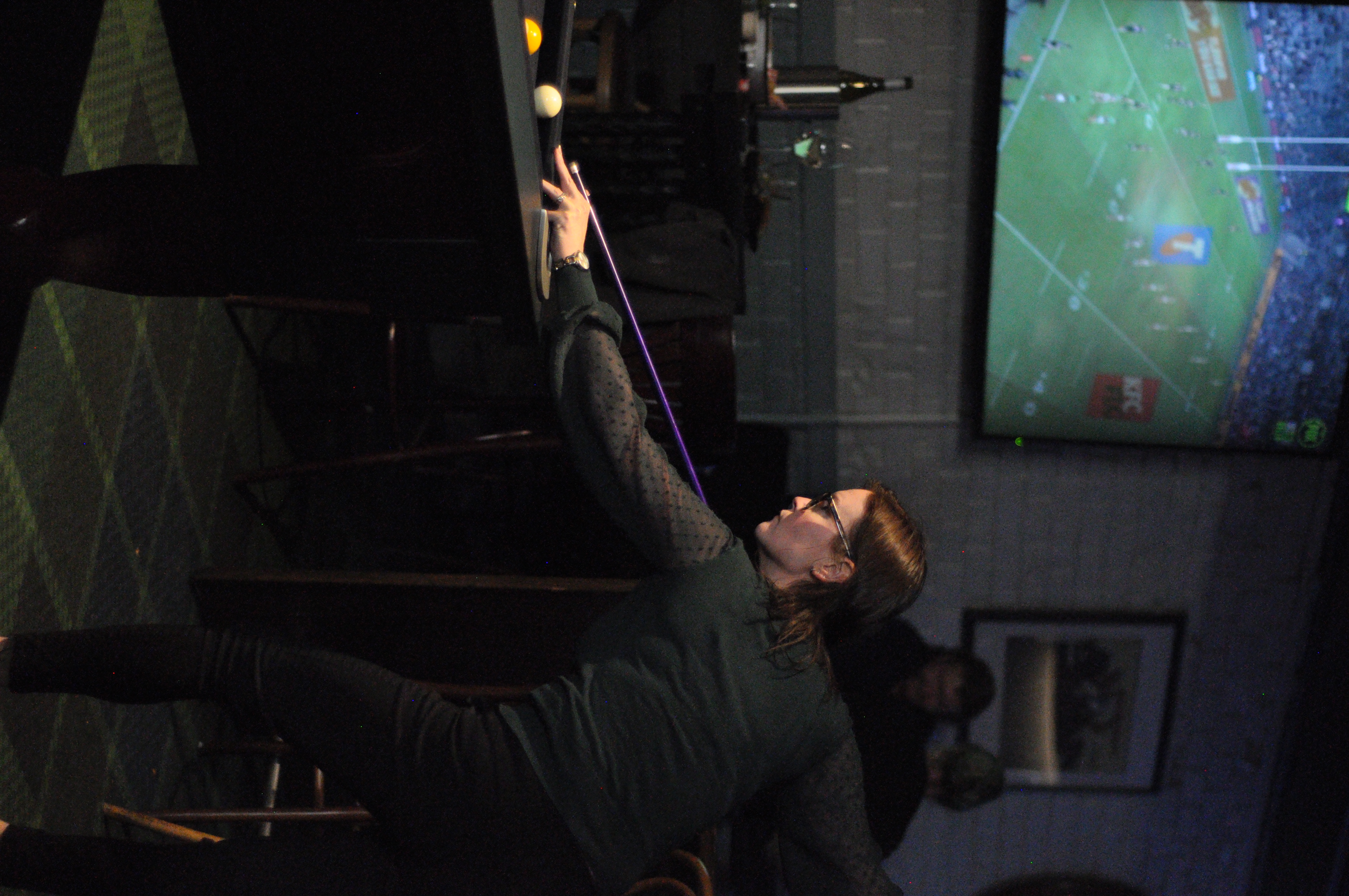 A person lining up a shot on a pool table inside a pub